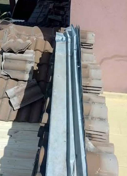 Cart&oacute;n apilado y l&aacute;minas de metal apoyados contra una pared rosa en el interior.