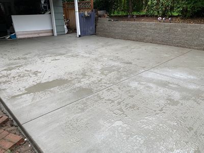 A concrete driveway with a brick wall in the background.
