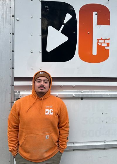 a man in an orange hoodie stands in front of a sign that says dc