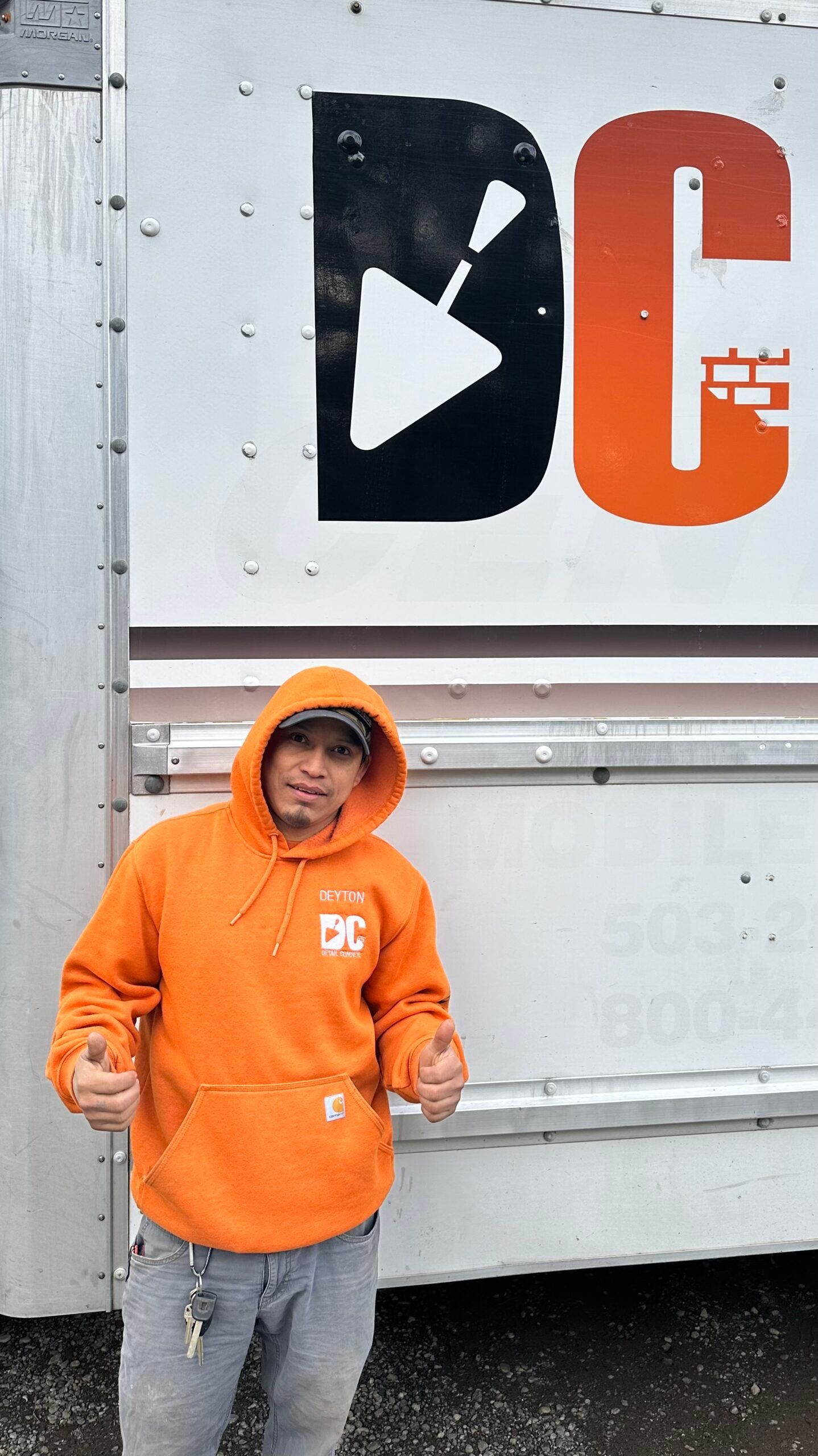 a man in an orange hoodie is giving a thumbs up