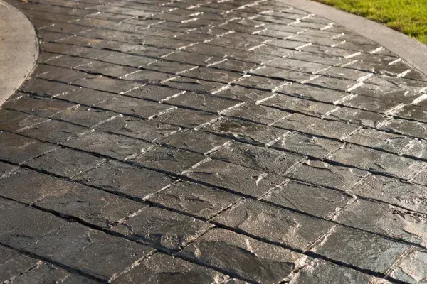 Brick-patterned concrete walkway, curving to the left, with a gray-toned finish.