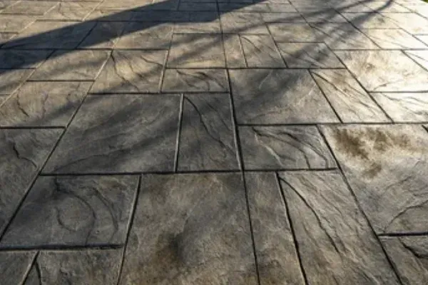 Stamped concrete patio with a stone-like texture, shaded by trees.