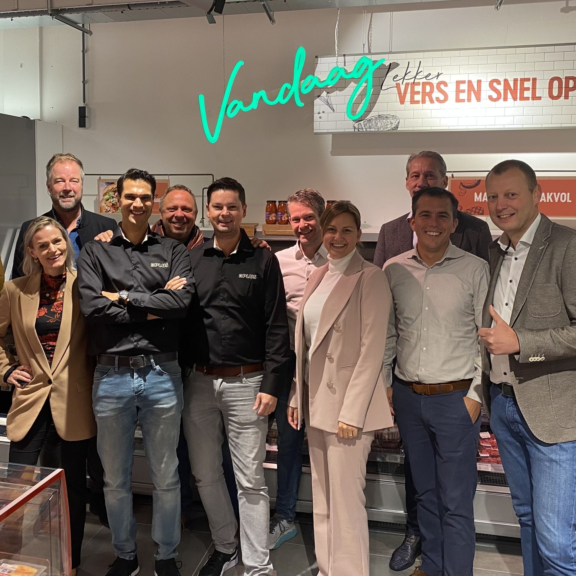 Een groep mensen poseert binnen voor een neonreclame en de tekst 