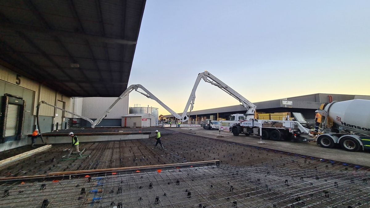 A concrete pump is being used to pour concrete into a warehouse.