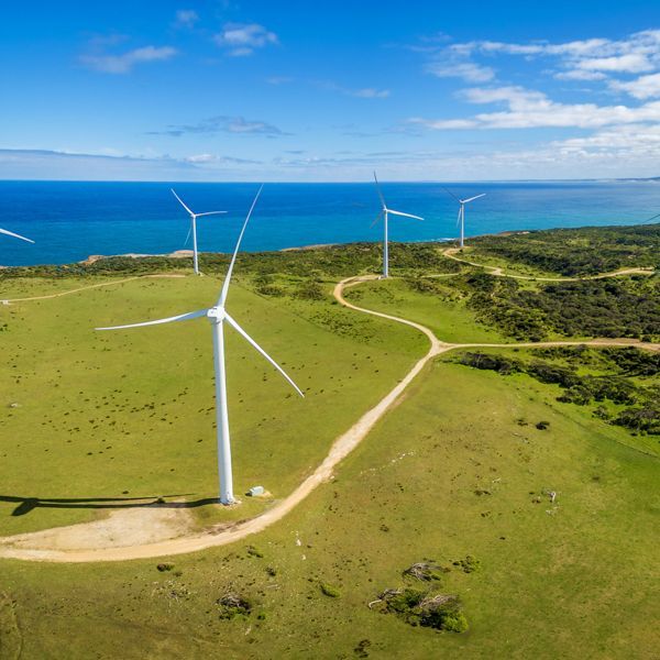 An aerial view of wind turbines on a hill near the ocean.