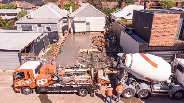 An aerial view of a concrete mixer truck pouring concrete into a driveway.