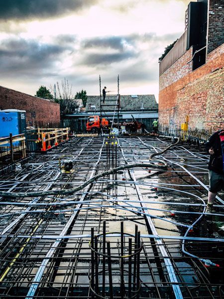A construction site with a brick building in the background.