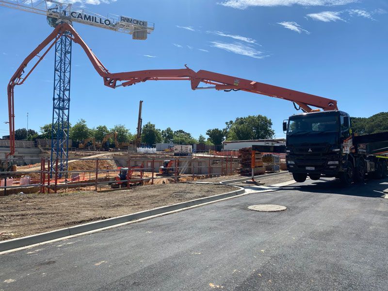 A truck is driving down a road next to a construction site.
