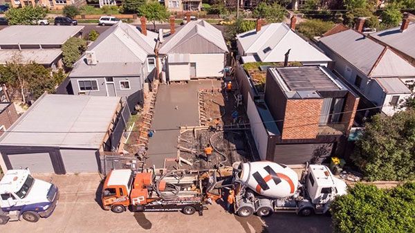 An aerial view of a concrete mixer truck pouring concrete into a driveway.