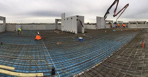 A large concrete floor is being poured on top of a building under construction.