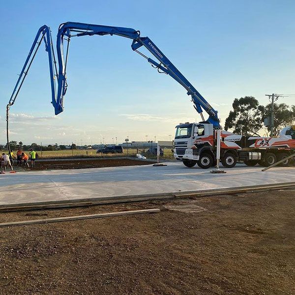 A truck with a crane attached to it is driving down a dirt road.