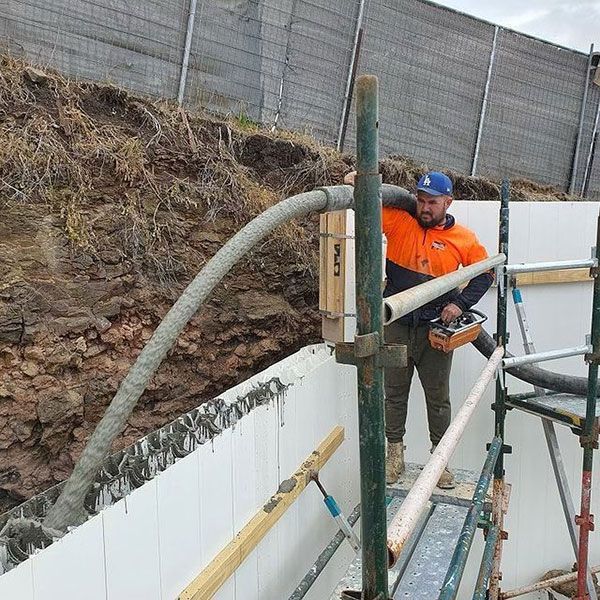 A man is standing on a scaffolding holding a hose.