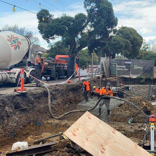 A concrete mixer truck is pouring concrete into a hole at a construction site.