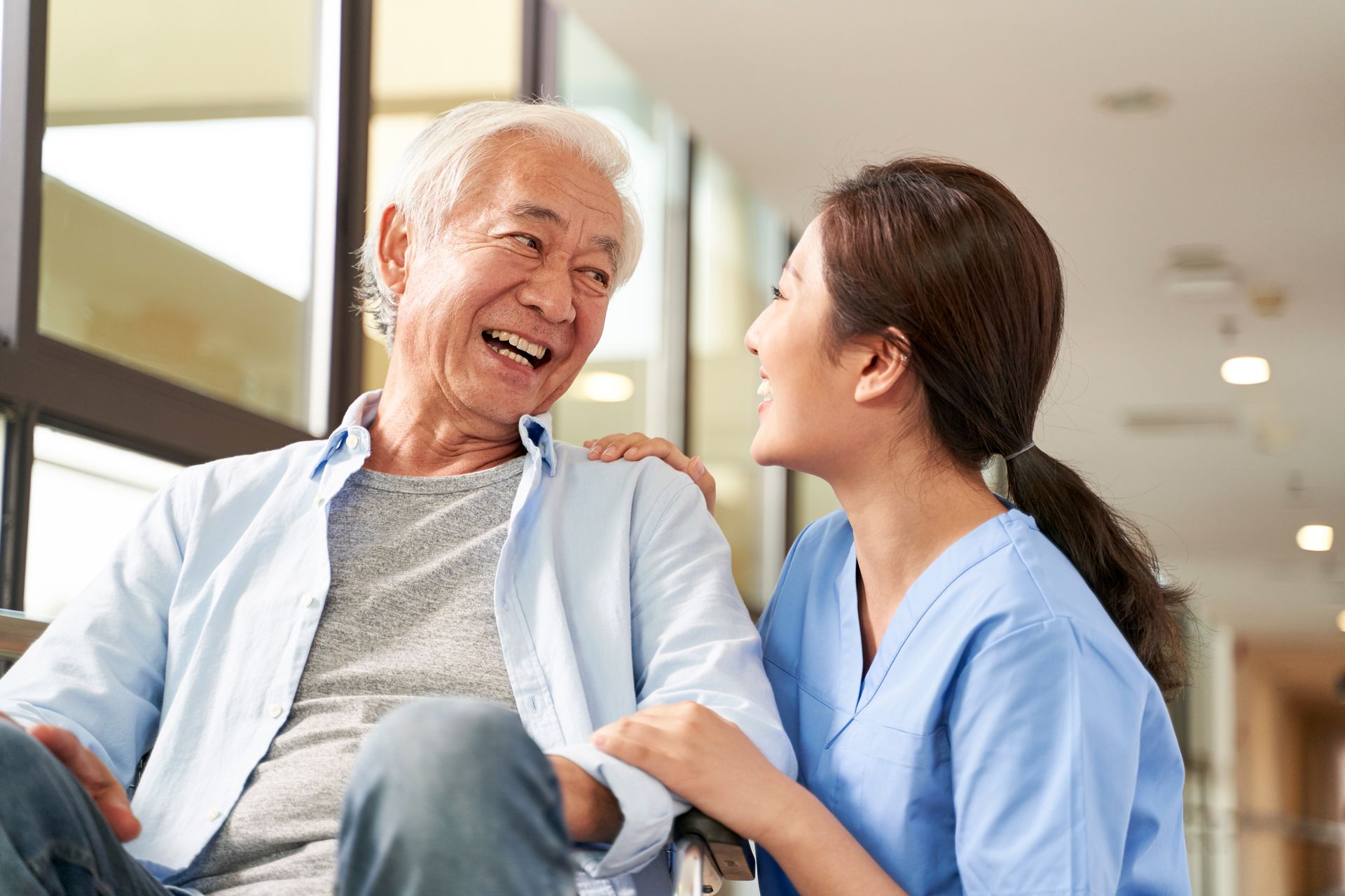 A caregiver is talking to an elderly man in a wheelchair.