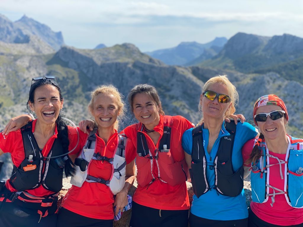 Un grupo de mujeres posa para una fotografía en la cima de una montaña.