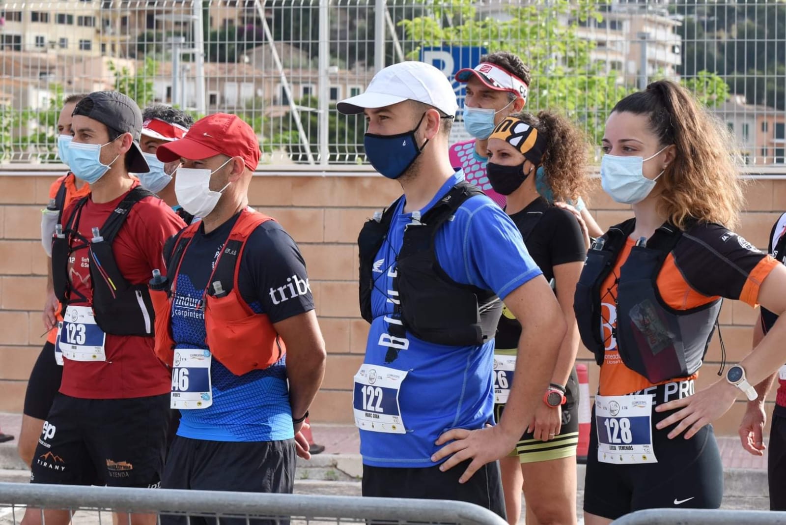Un grupo de personas que llevan mascarillas están de pie una al lado de la otra.