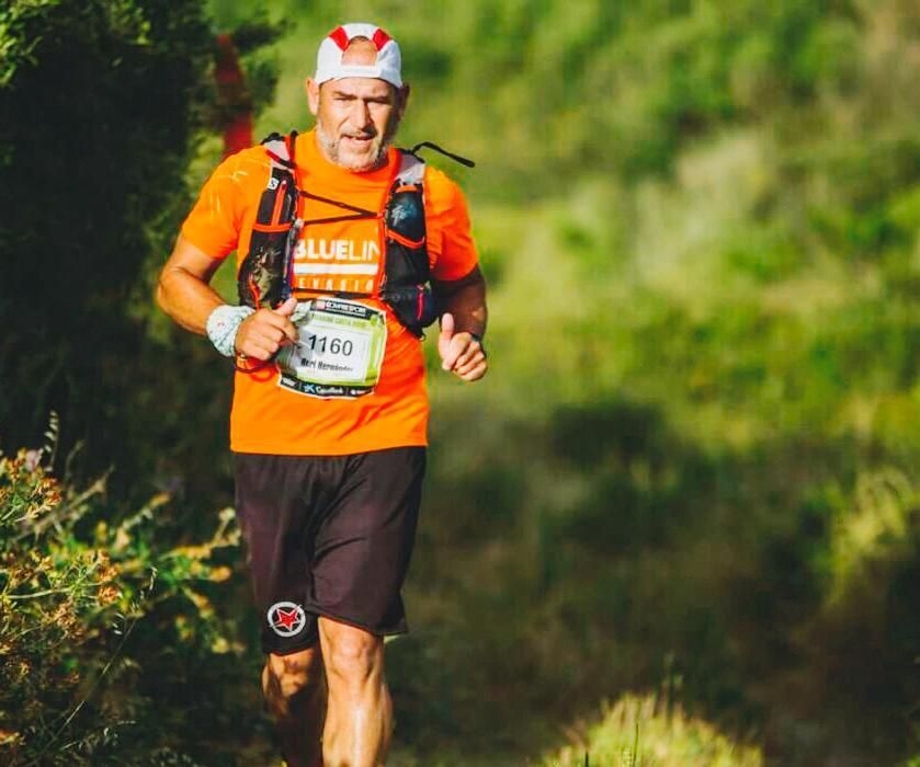 Un hombre con una camisa naranja corre por un bosque.