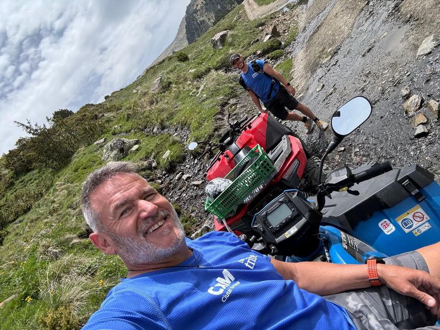 Un hombre con una camisa azul está sentado en un vehículo todo terreno rojo.