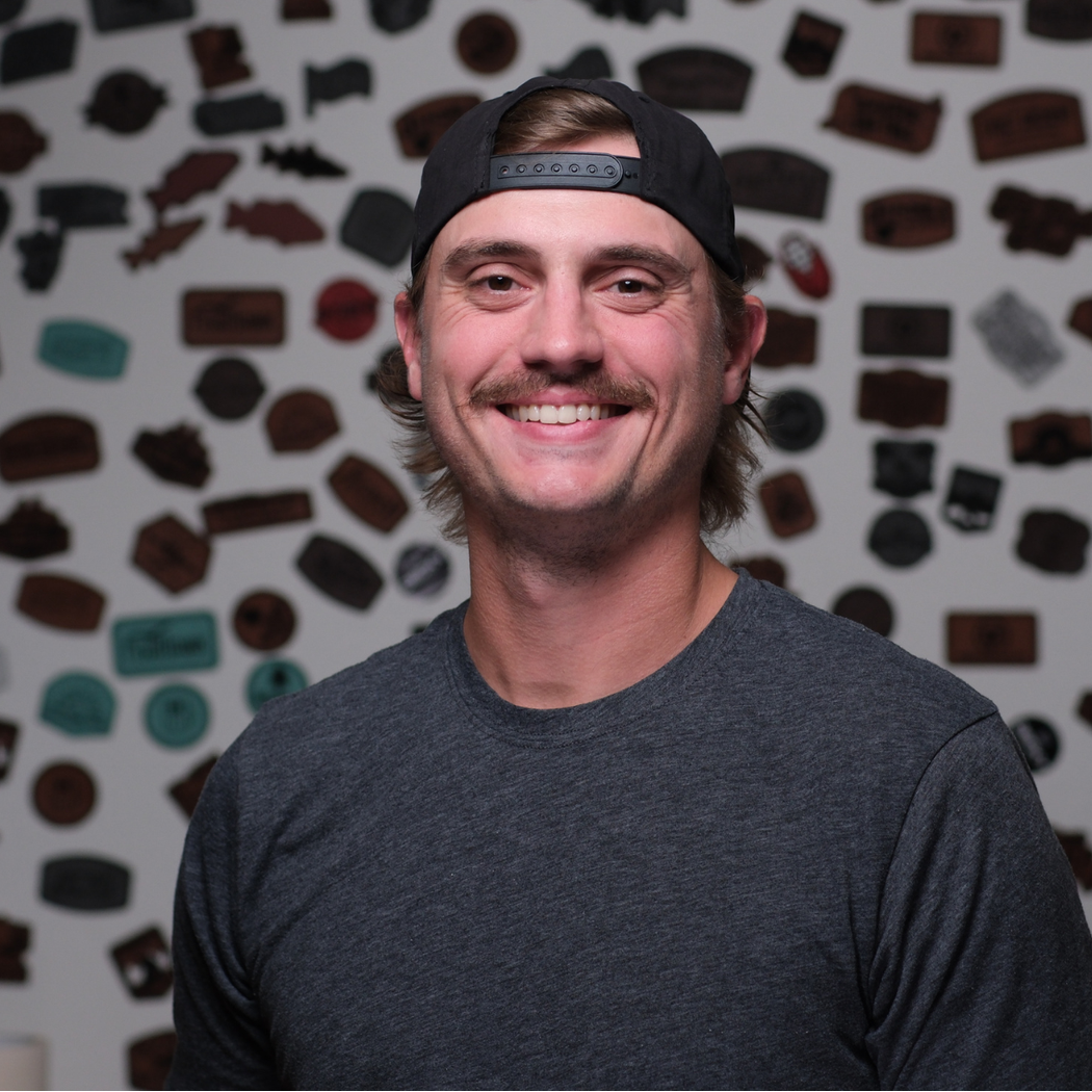 A man wearing a baseball cap and a grey shirt is smiling