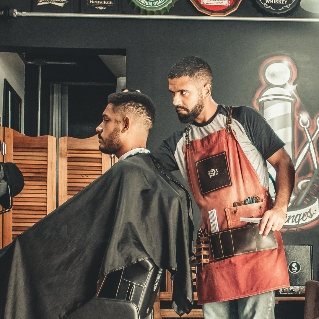 A man is getting his hair cut by a barber in a barber shop.
