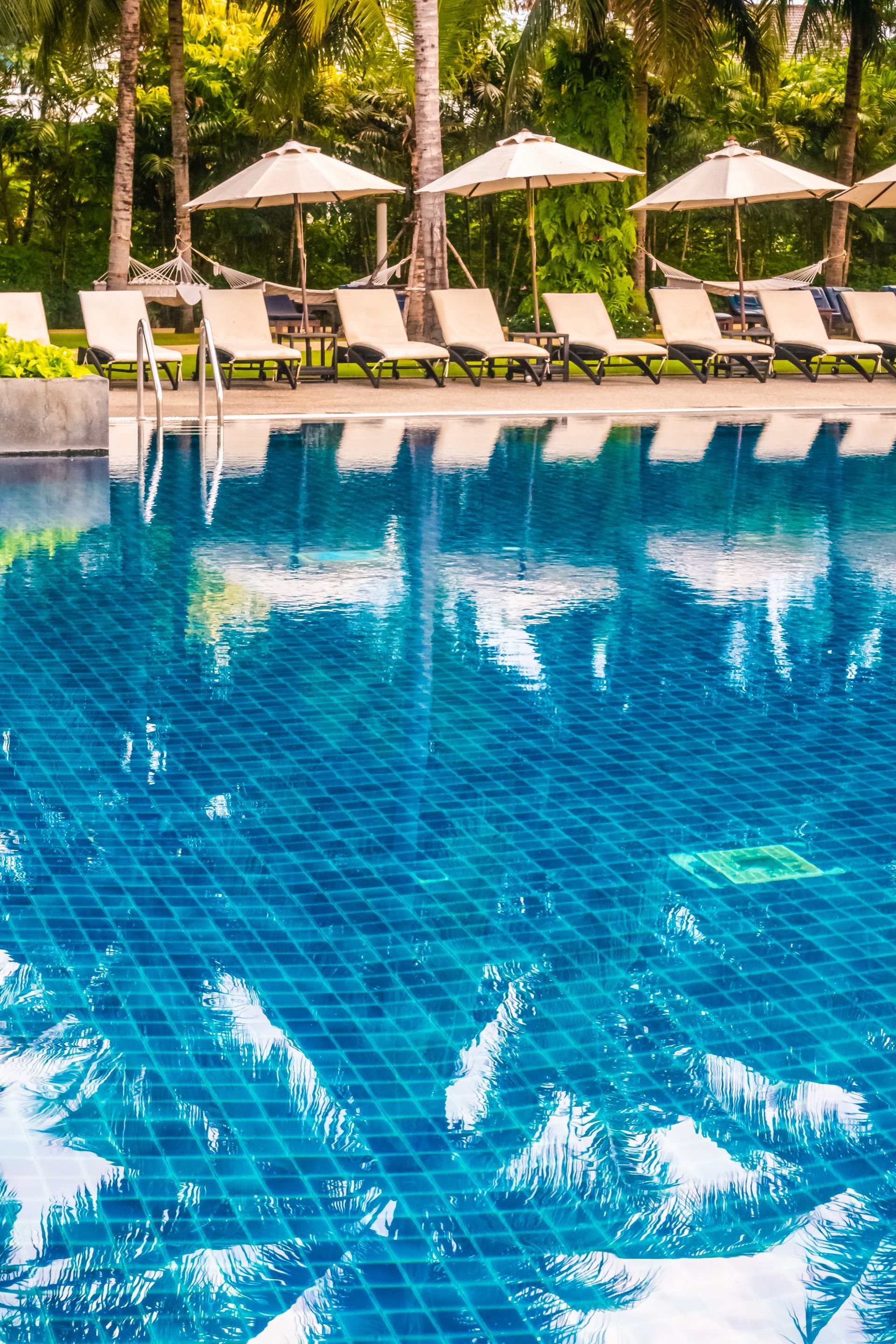A large swimming pool surrounded by chairs and umbrellas.