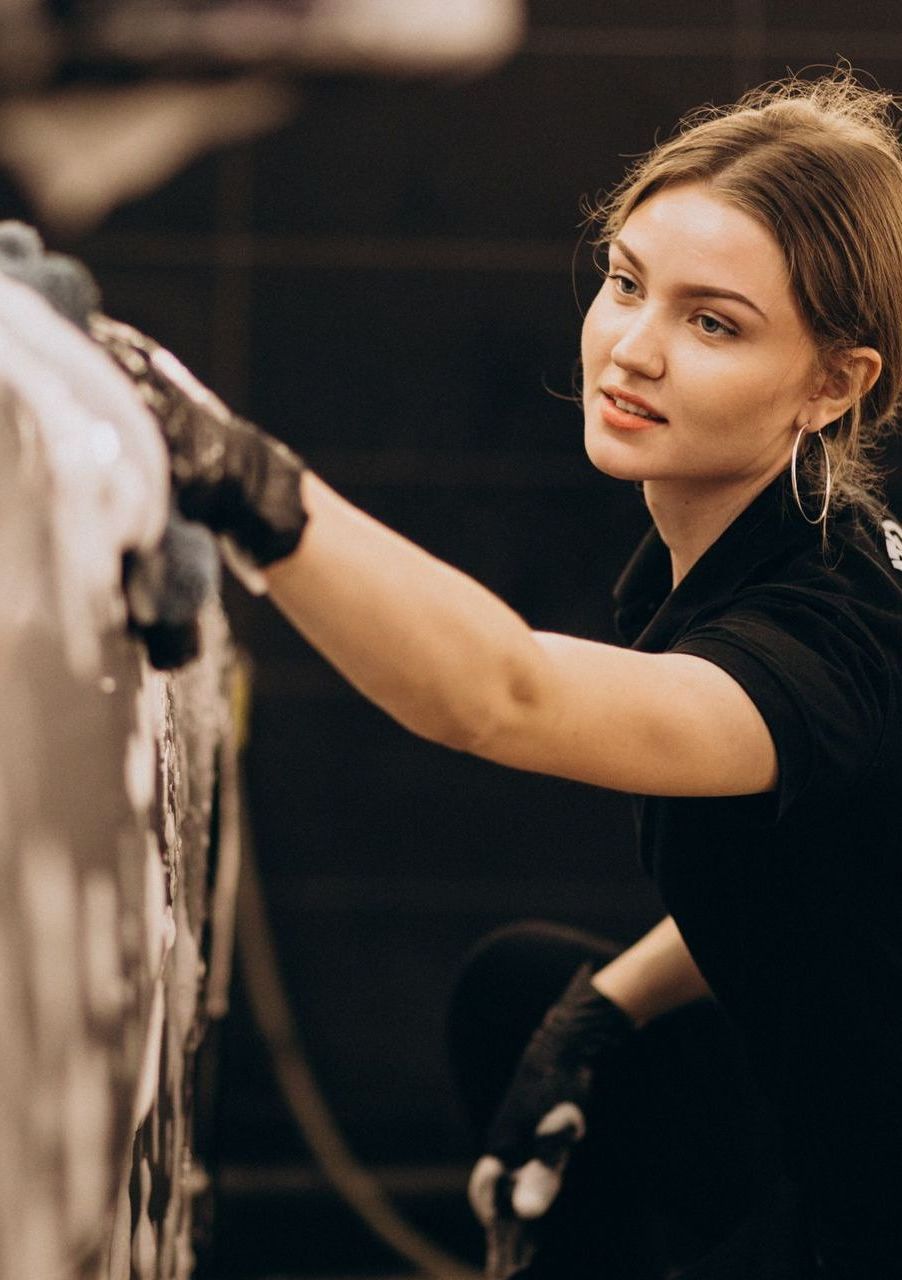 A woman is washing a car in a car wash.