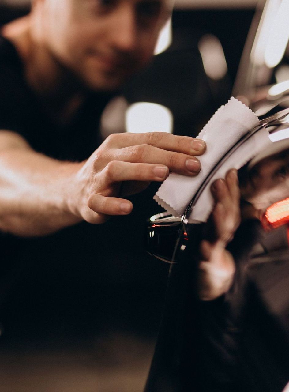 A man is cleaning a car with a cloth.