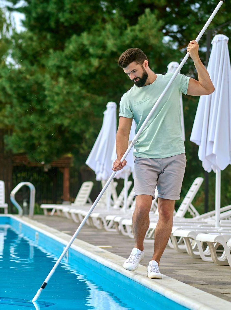 A man is cleaning a swimming pool with a net.