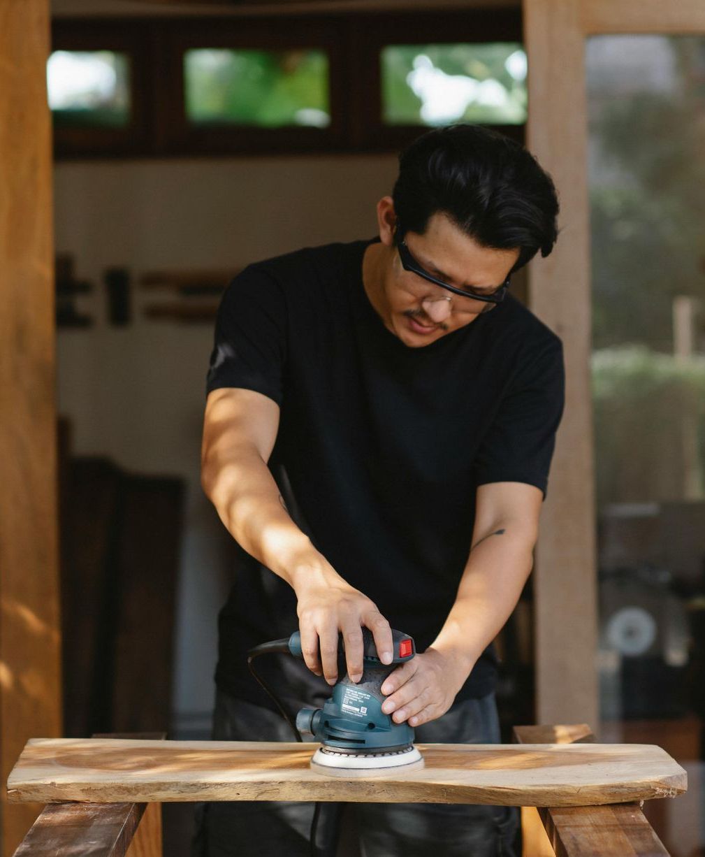 A man is sanding a piece of wood with a sander.