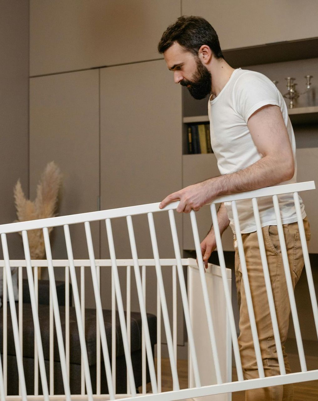 A man is holding a white railing in a living room.