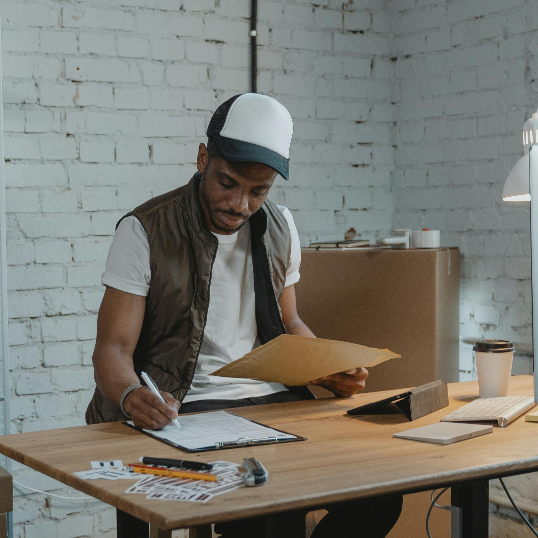 A man is sitting at a desk holding a piece of paper and a pen.