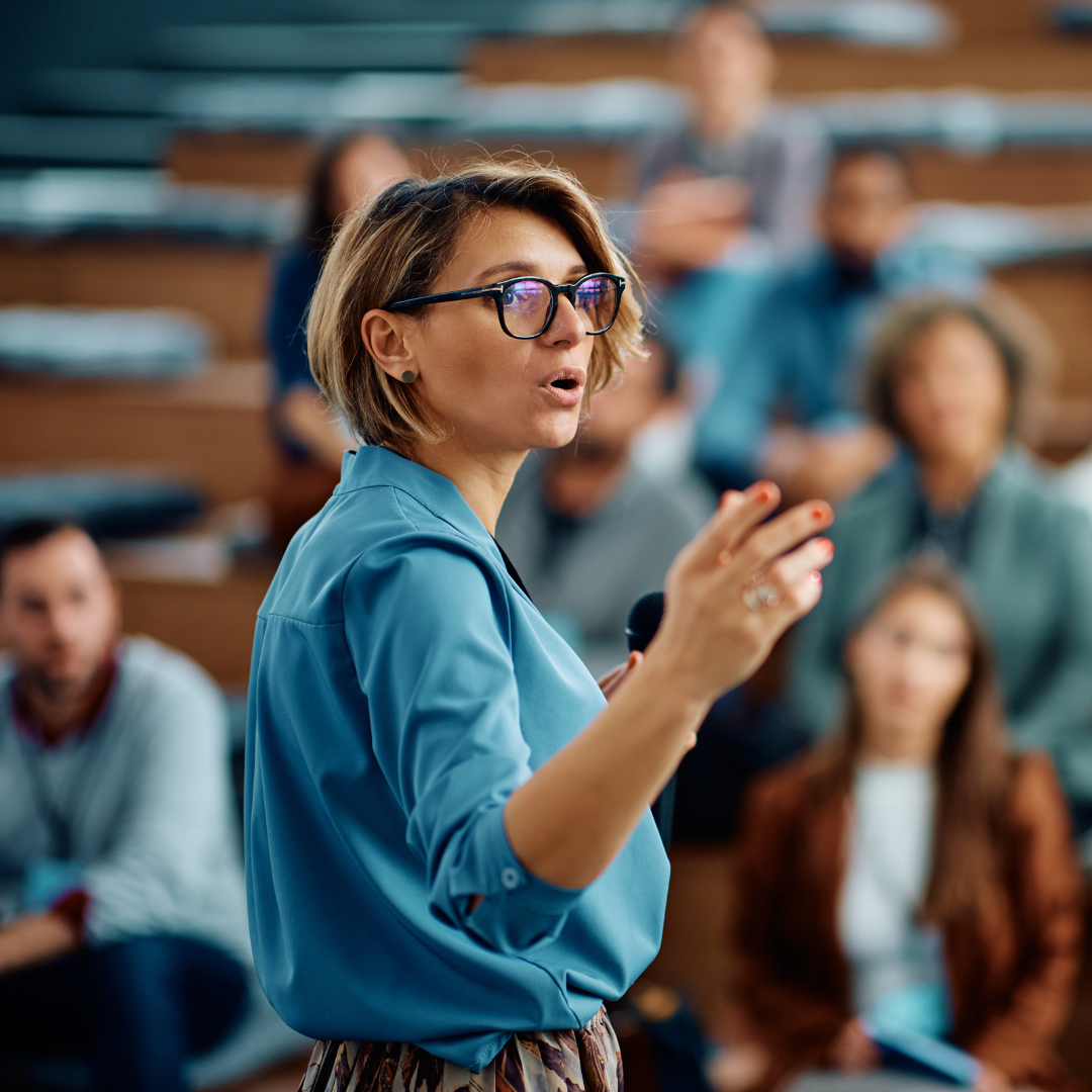 A woman is giving a presentation to a group of people in a lecture hall.