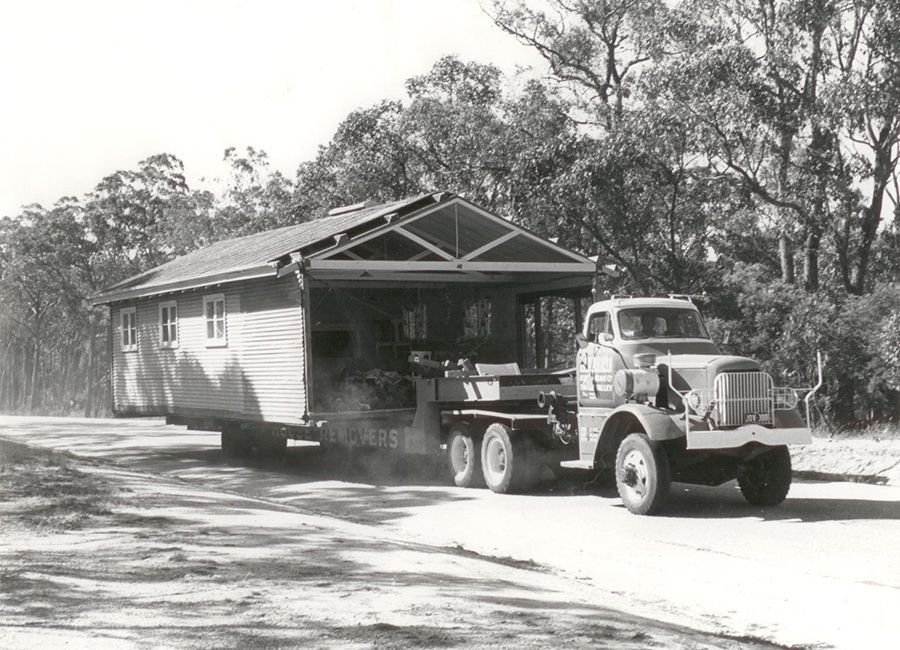 A black and white photo of a truck pulling a house