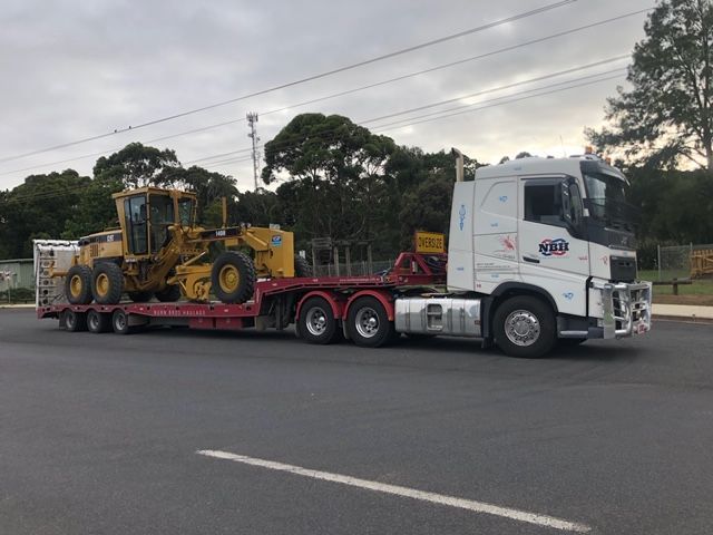 A semi truck is carrying a bulldozer on a trailer.