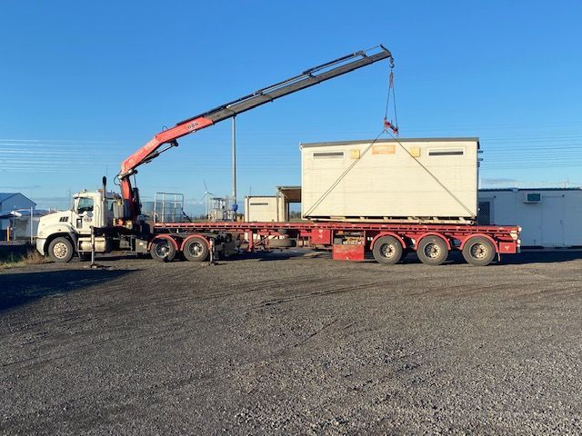A truck with a crane attached to it is carrying a large box.