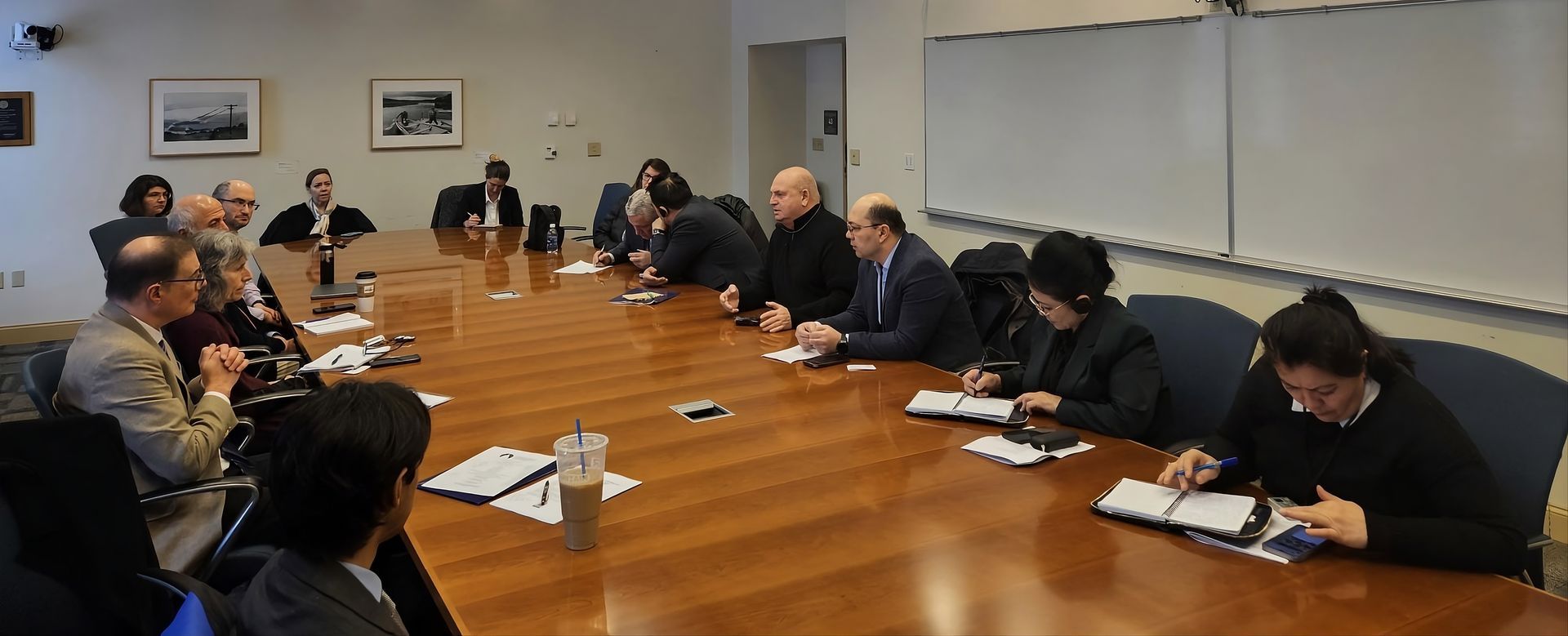 People seated around a conference table in a meeting room, taking notes.