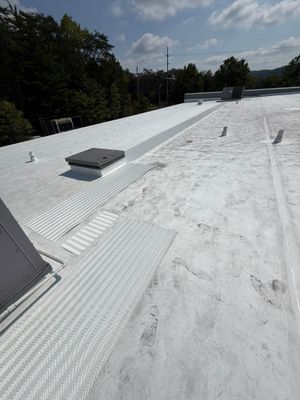 White commercial flat roof with vents and HVAC units under a clear sky