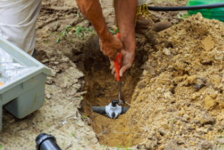 Sprinkler expert installing underground pipe for lawn sprinkler at commercial business in Cheyenne.