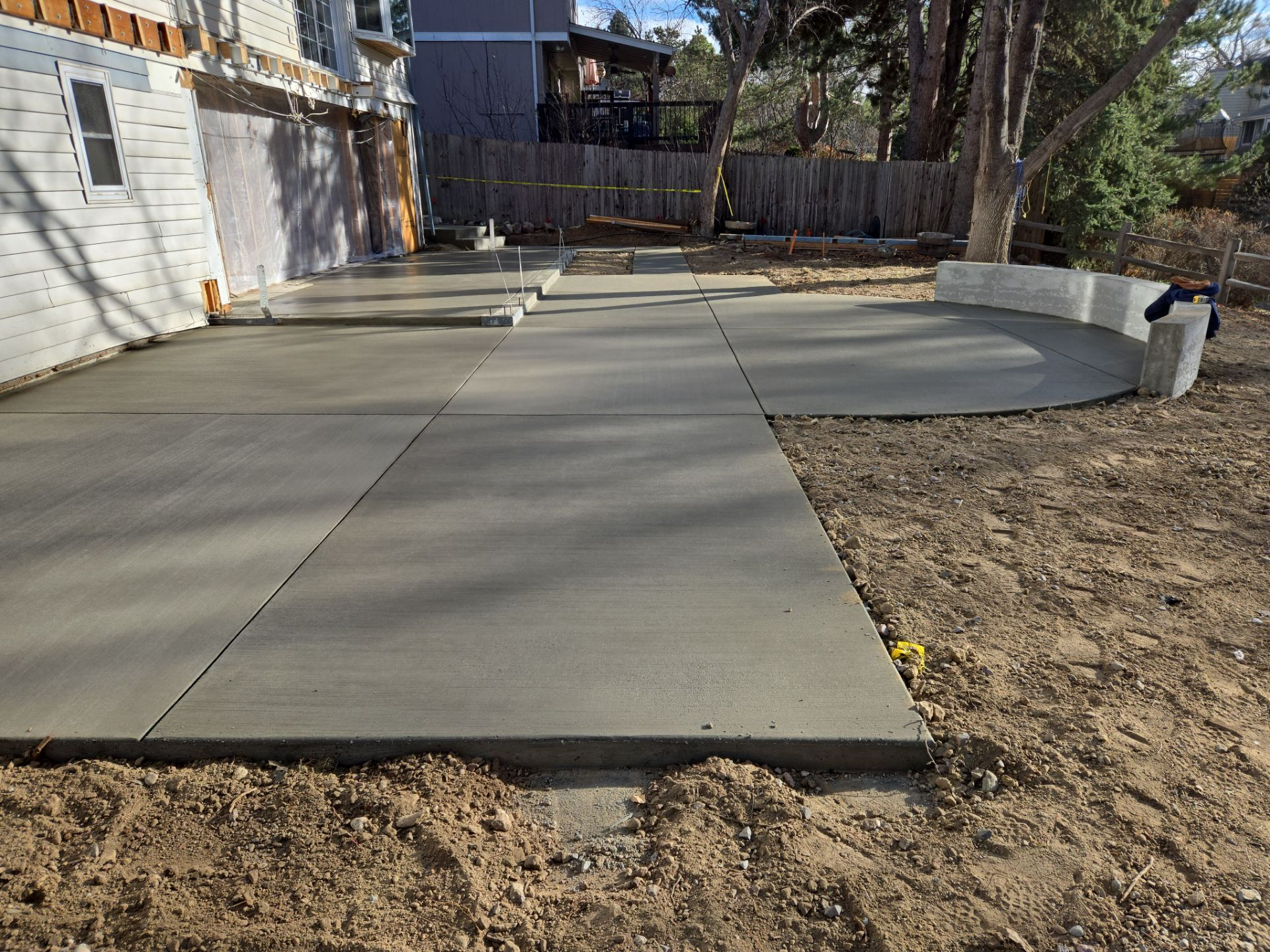 Newly poured concrete patio and walkway in a backyard setting.