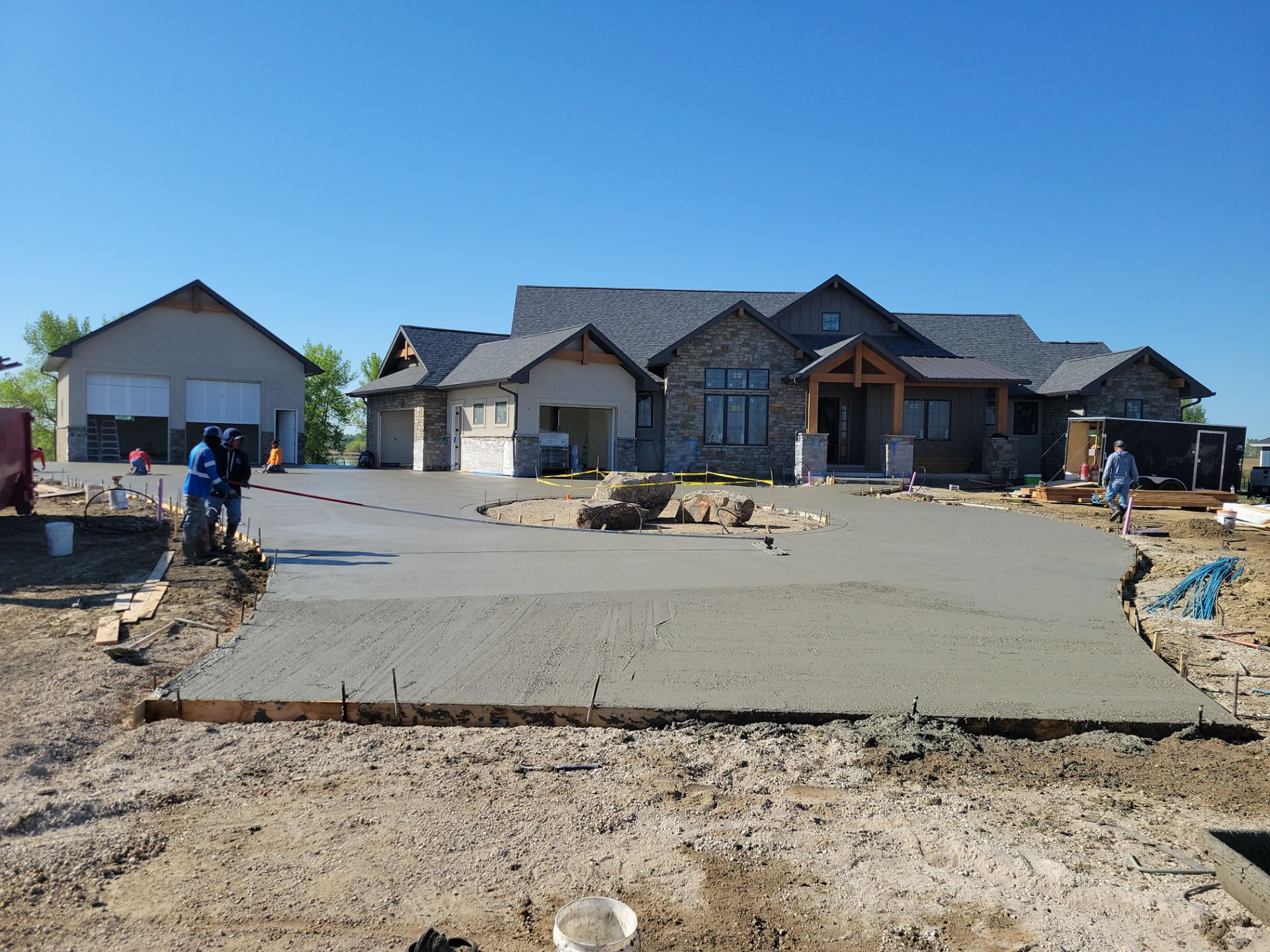 Newly poured concrete driveway in front of a large house under construction.