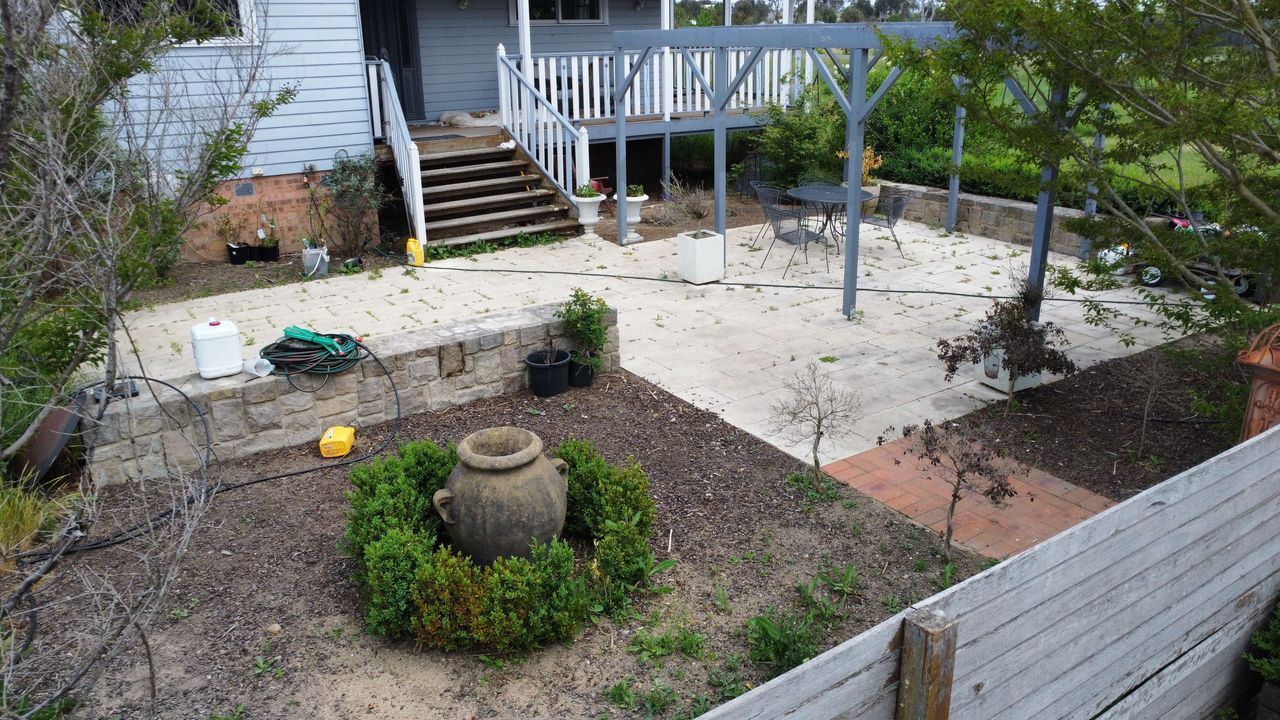 Before A Brick Walkway Leading To A Backyard Filled With Lots Of Plants And Trees — Canberra Home and Garden Maintenance in Tuggeranong ACT
