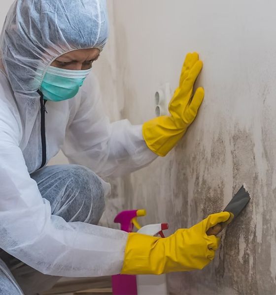 A person wearing a mask and yellow gloves is cleaning a wall.