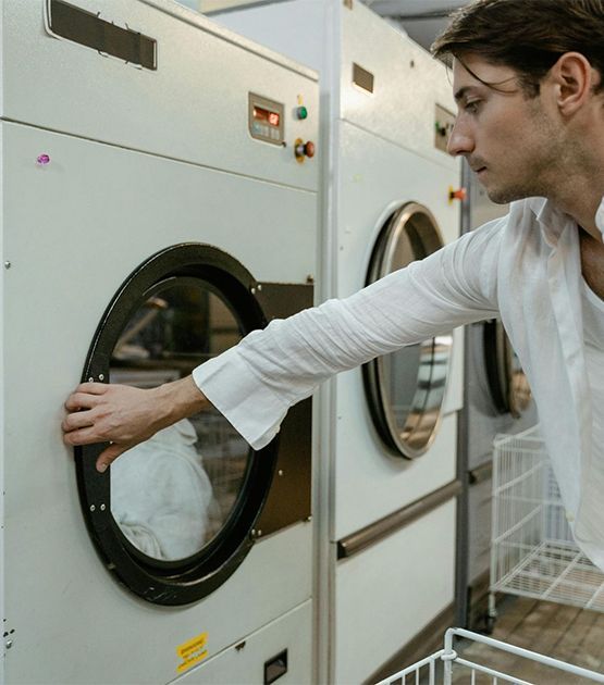 Man opening a washing machine door in a laundromat.
