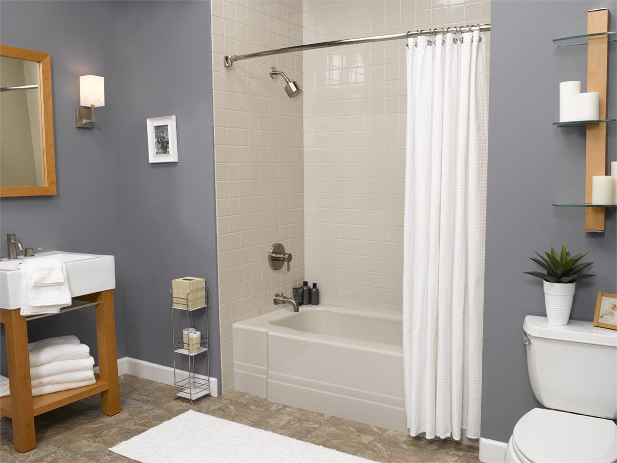 A bathroom with a tub , toilet , sink and mirror