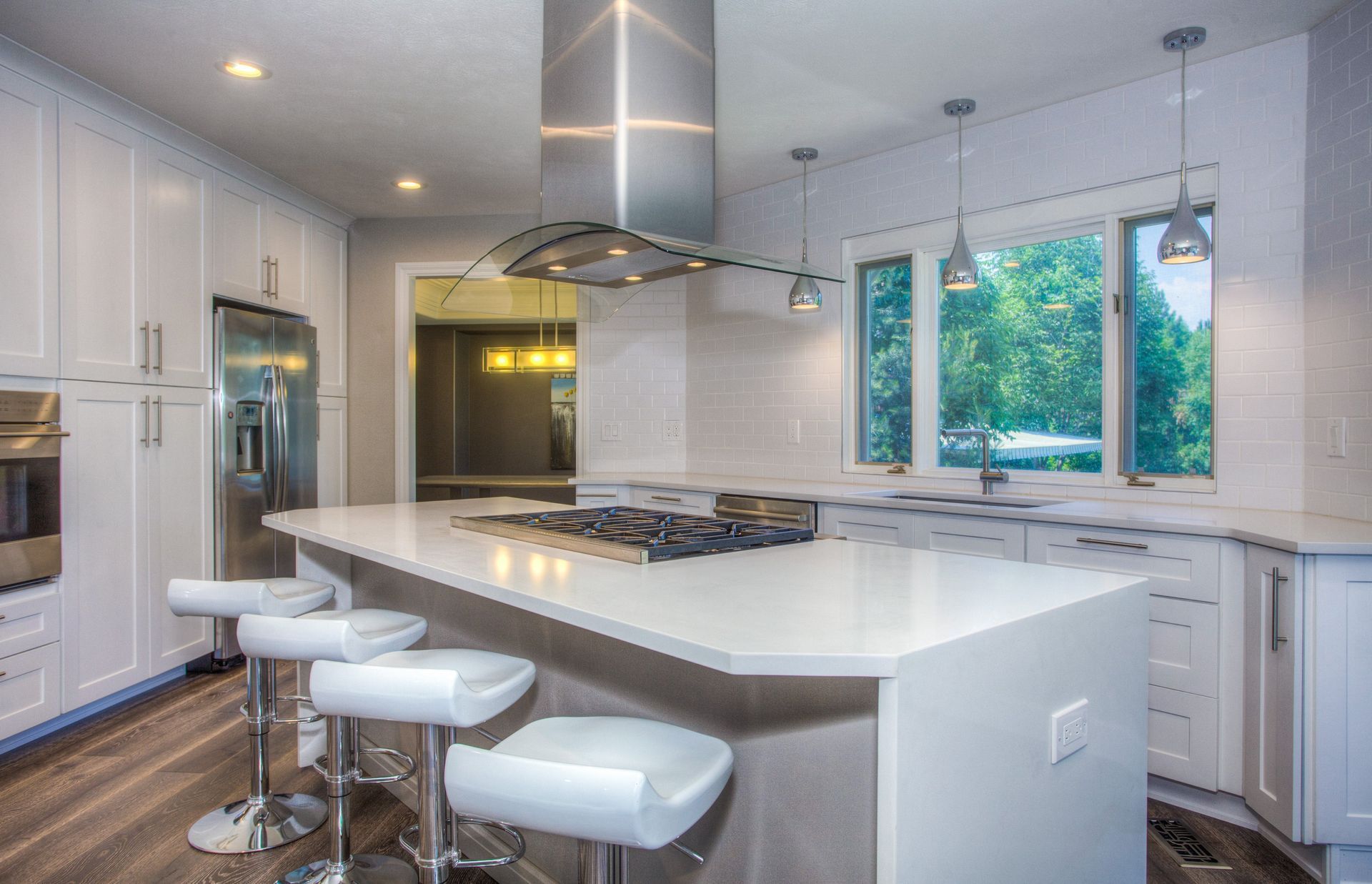 Bright modern kitchen with white cabinets, large island, barstools, and stainless steel appliances