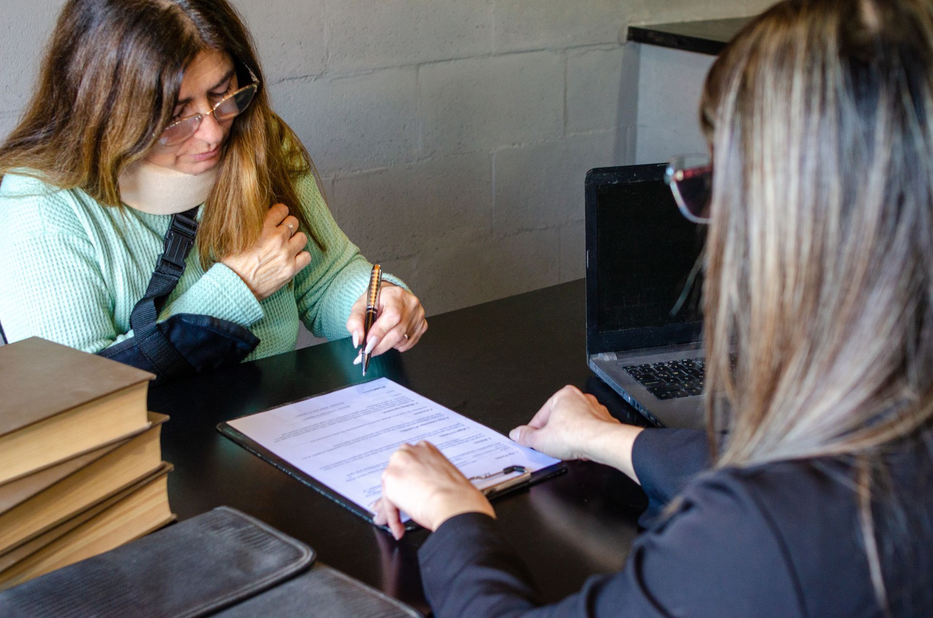 Injured woman signing an insurance claim or legal contract with lawyer.