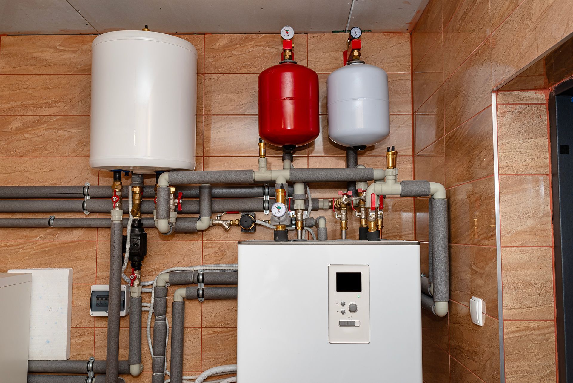 A room with a boiler and a bunch of pipes hanging from the ceiling.