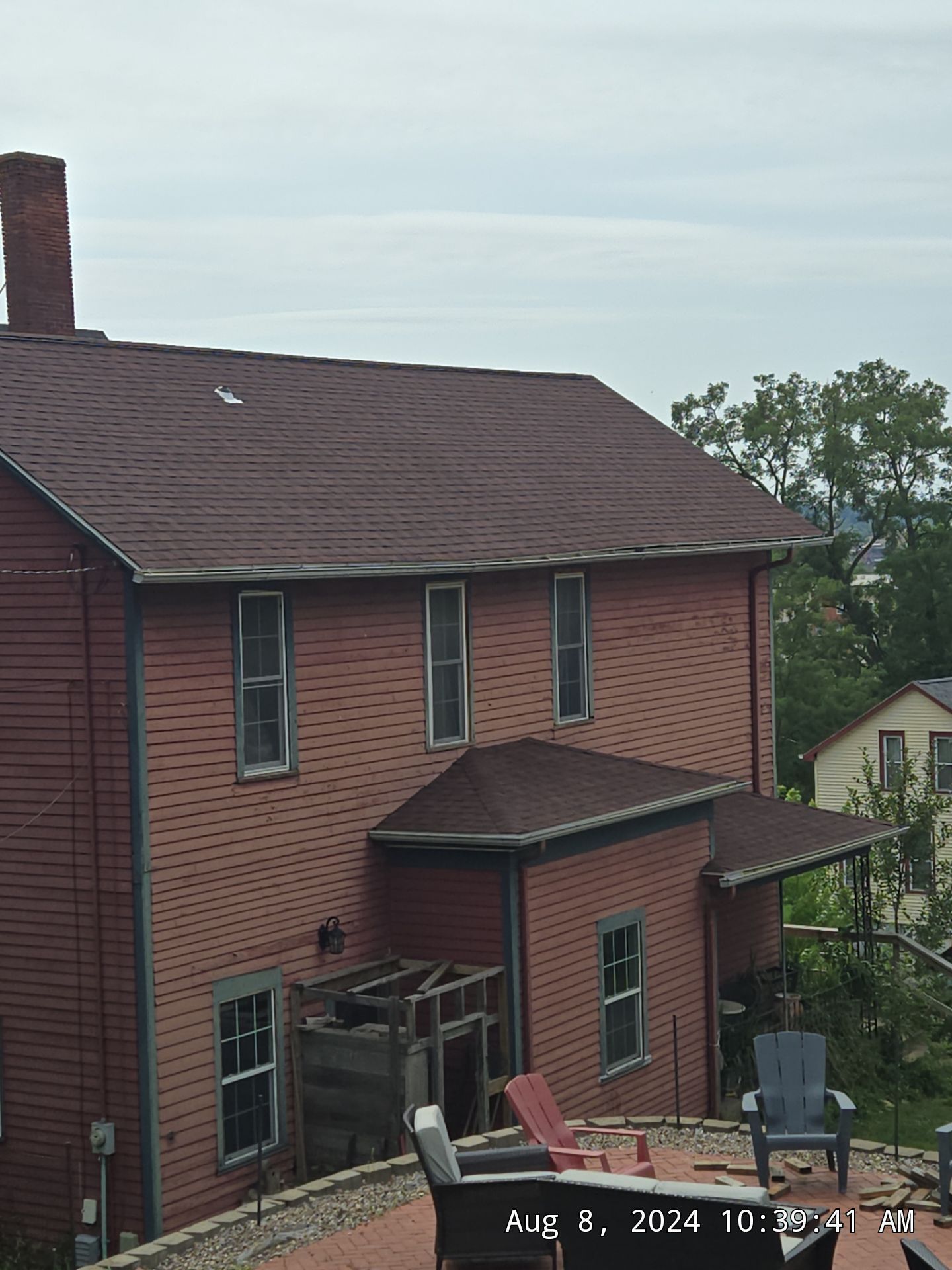 Red brick house with dark roof and chimney, seen from above.
