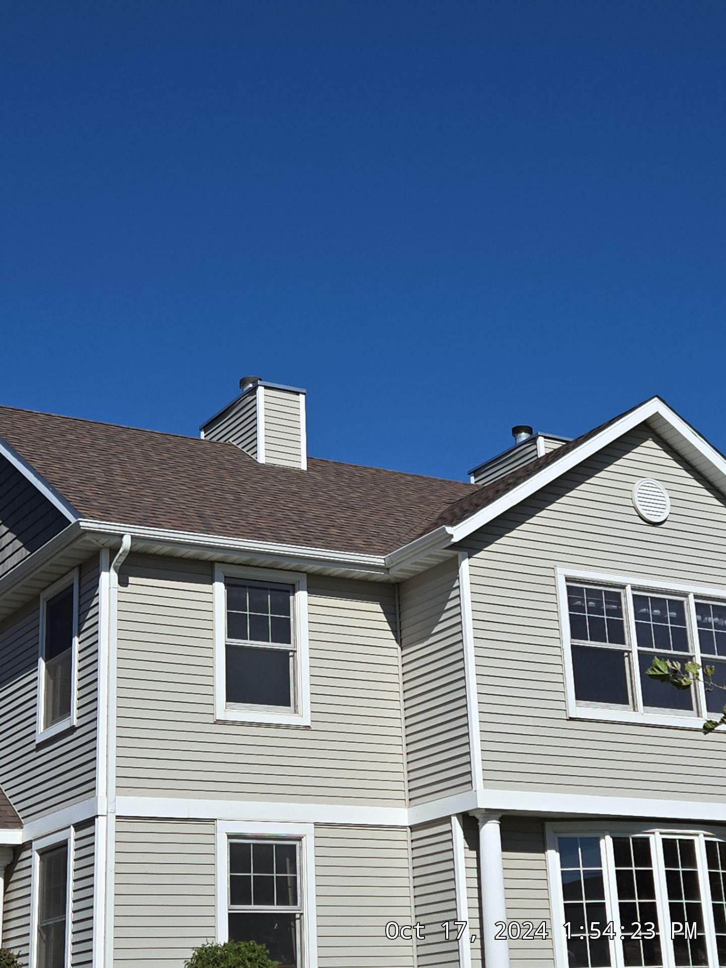 Two-story gray house with white trim under a bright blue sky