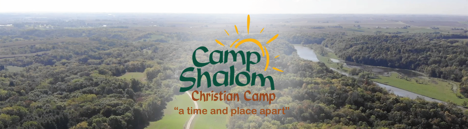 Aerial view of a wooded camp with the Camp Shalom Christian Camp logo centered over the landscape